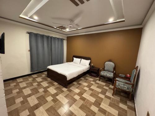 a bedroom with a bed and a chair in it at Summit Hotel Skardu in Skardu