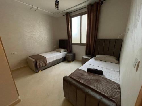 ein Schlafzimmer mit zwei Betten und einem Fenster in der Unterkunft Coucher de soleil à Saïdia in Saidia 