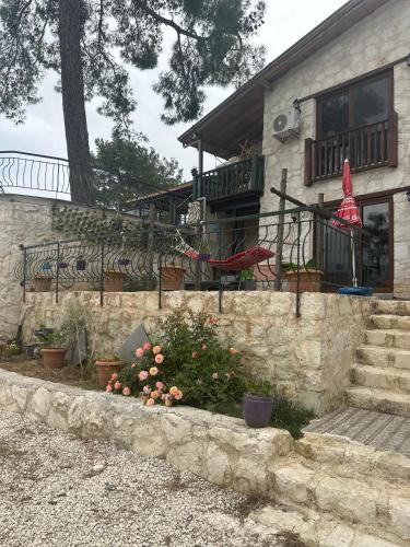 a house with a stone wall and flowers in front of it at Kandybos Eco Farm Village in Kas