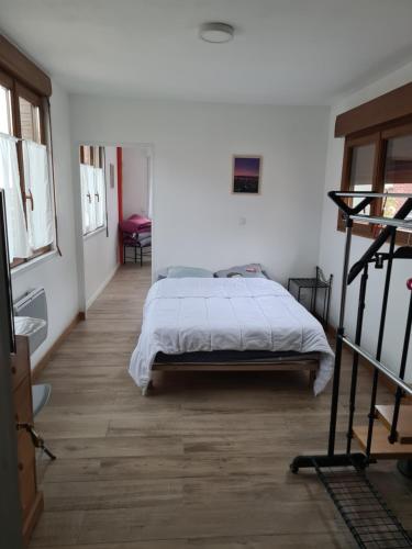 une chambre avec un lit dans une pièce blanche dans l'établissement La maison du bonheur, au Crotoy