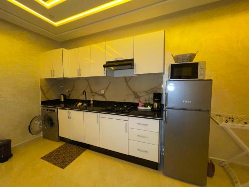 eine Küche mit Kühlschrank und Mikrowelle in der Unterkunft Coucher de soleil à Saïdia in Saidia 