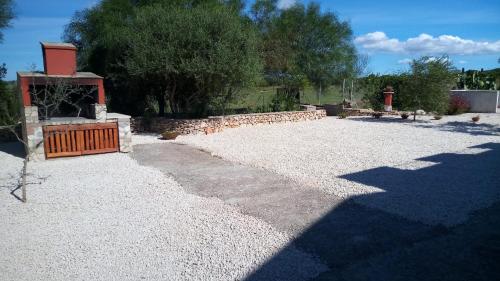 a gravel yard with a stone wall and a fireplace at Olmedo Casa Vacanze in Olmedo