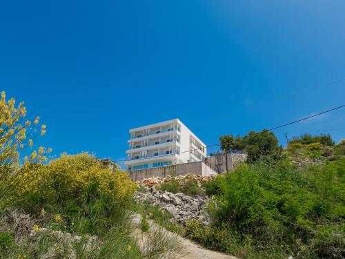 a building on top of a hill with plants at Sunset Shoreline Saranda - Sea View - Free Private Parking - Pool in Sarandë