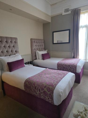 a hotel room with two beds with purple sheets at Maples House Hotel in Dublin