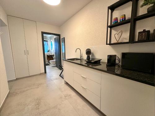 una cucina con mobili bianchi e un piano di lavoro di Romantic coastal apartment with sea views a Komarna