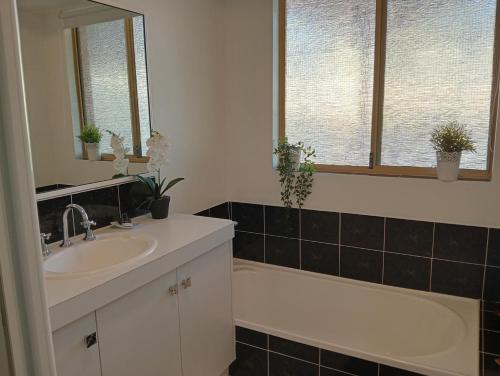 a bathroom with a sink and a bath tub and windows at Christian couples retreat, pet friendly BnB in Dawesville