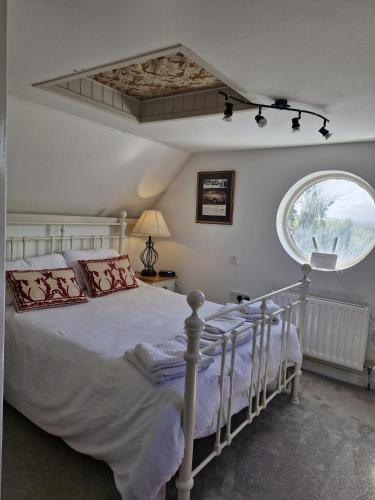 a bedroom with a white bed and a large window at The Mews, Ballydehob in Ballydehob
