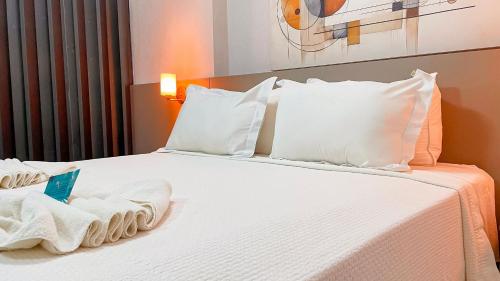 a bedroom with a bed with white sheets and pillows at Flat FM20 Cabo Branco #L5 - By Almare in Tambaú