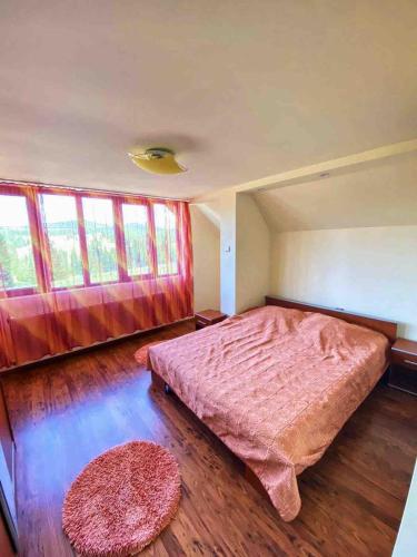 ein Schlafzimmer mit einem großen Bett und zwei Fenstern in der Unterkunft Dreamcatcher in Piatra Fântânele