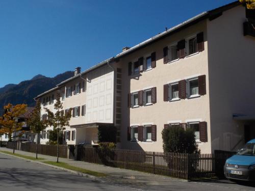 a white building with a fence next to a street at Gartenblick in Mittenwald