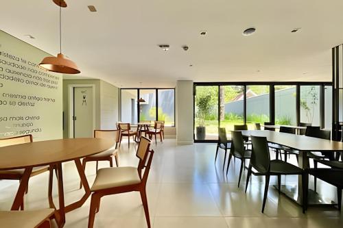 a dining room with tables and chairs and windows at Incrivel, Apto 1 Quarto Bem Prox Batel in Curitiba
