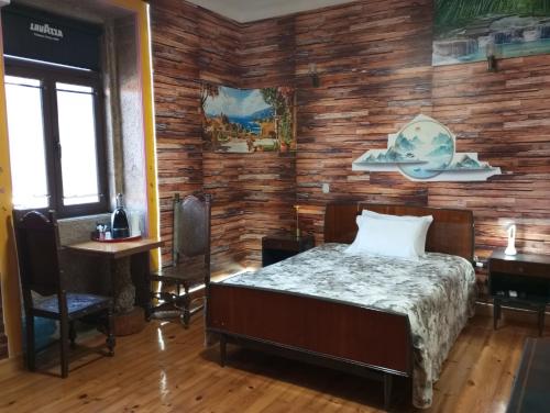 Un dormitorio con una cama y una pared de madera. en Albergue do Visconde, en Touguinha