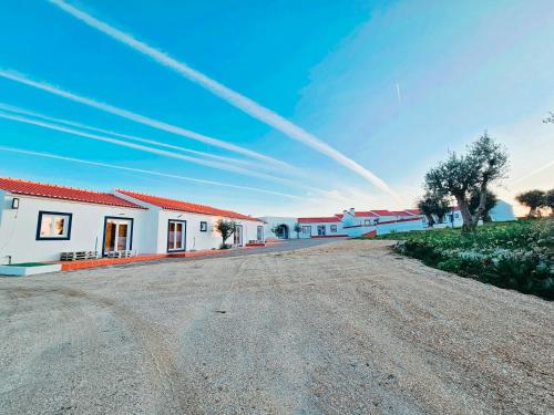 a row of white houses with red roofs on a dirt road at Herdadinha in Vimieiro