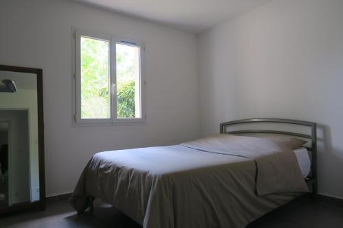a white bedroom with a bed and a window at L'embellie in Châteaurenard