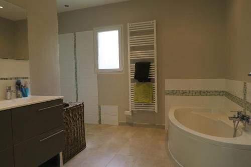 a bathroom with a tub and a sink and a window at L'embellie in Châteaurenard