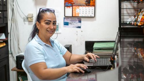 a woman sitting at a counter with a laptop at Santa Helena Suite in Acacías