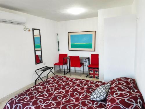 a bedroom with a bed and a table with red chairs at El depa de los cactus in Progreso