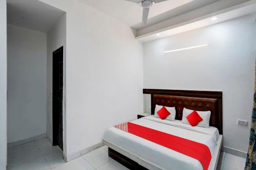 a bedroom with a bed with red and white pillows at Hotel O Elite Signature in Indirapuram