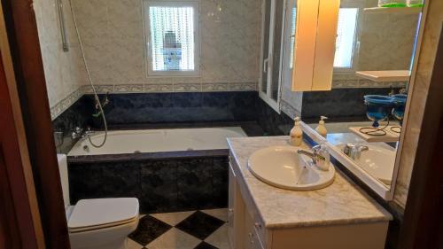 a bathroom with a sink and a tub and a toilet at Precioso chalet con gran algarrobo y piscina privada in La Jara