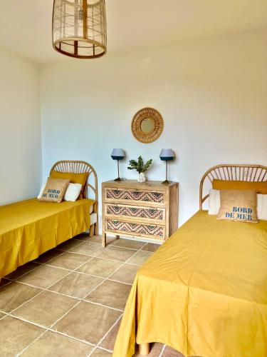 - une chambre avec 2 lits et une table avec une table de chevet dans l'établissement La Bastide d'Aiguebelle, au Lavandou
