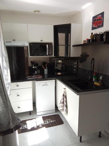 une cuisine avec des armoires blanches et un comptoir noir dans l'établissement Maison coquette camarguaise, à Codognan