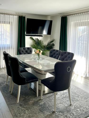 a dining room table with chairs and a television at Zakątek u Ili in Rzepiska