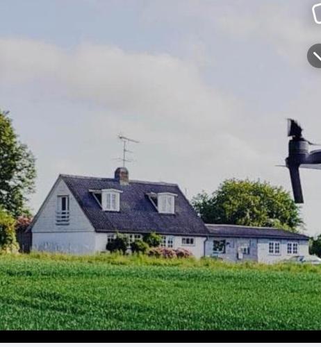 a white house with a black roof in a field at Den gamle smedie in Holbæk
