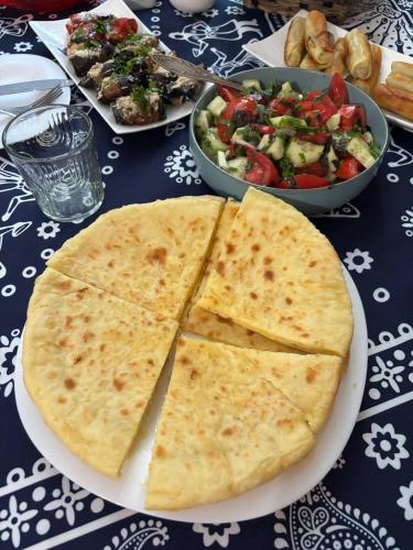 una mesa con un plato de comida y una ensalada en Hill Guesthouse - Wine Cellar, Fish Farm & Organic Cuisine, en K'eda