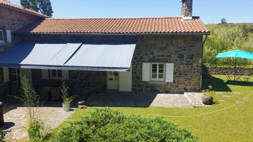 a stone house with a blue awning on it at Gîte Le Parc - Domaine Le Clos de Vourzac in Sanssac-lʼÉglise