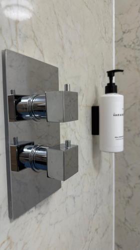 a bathroom with a soap dispenser on a wall at Watermead House in Chard