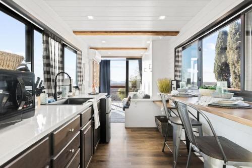 a kitchen with a sink and a counter with chairs at Rooftop Spa Tiny Cargo Home Farm Experience in Tulare