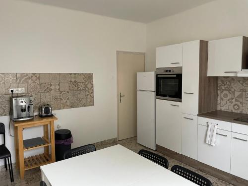 a kitchen with white appliances and a table and chairs at Elvira Vendégház in Kisbodak