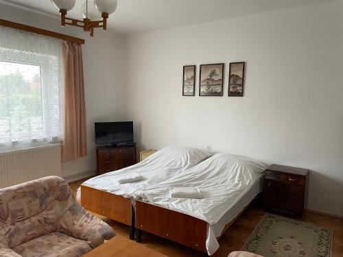a bedroom with a bed and a chair at Elvira Vendégház in Kisbodak