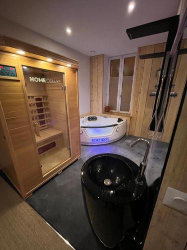 La salle de bains est pourvue d'un lavabo noir et d'une baignoire. dans l'établissement Loubottine sauna and balnèo, à Romans-sur-Isère
