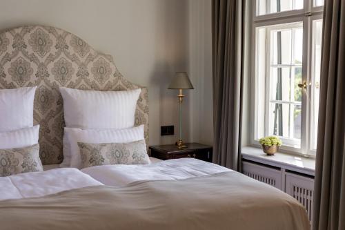 a bedroom with a white bed and a window at Schlosshotel Neustrelitz in Neustrelitz