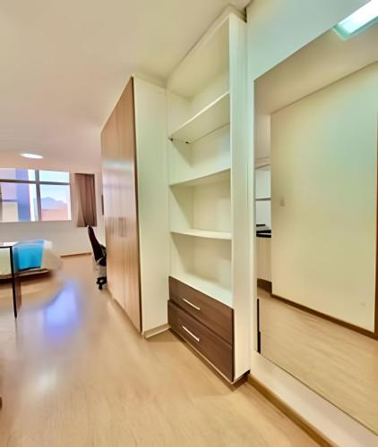 an office room with a large wall of shelves at Exuberante studio Bem no centro da Cidade in Curitiba