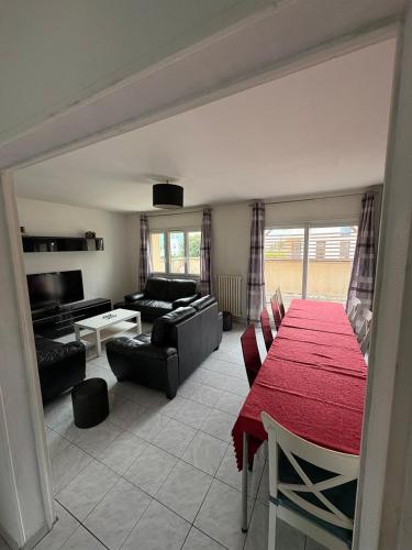 - un salon avec une table rouge et un canapé dans l'établissement Maison spacieuse proche de Caen, à Colombelles