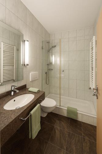 a bathroom with a sink and a toilet and a tub at Fränkischer Hof Hotel Garni in Alzenau