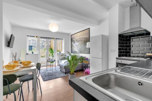 a kitchen and living room with a sink and a table at The Connected Garden Flat - Parking, Work & Play, 3x in Colindale