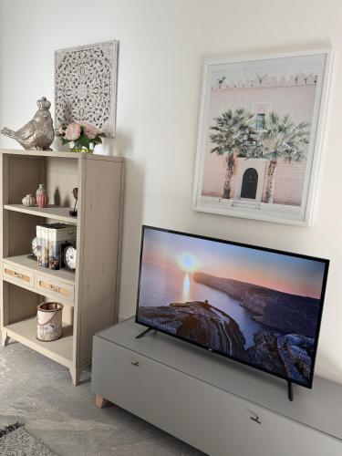 a flat screen tv sitting on a dresser in a living room at Stylish Boutique House - Turquoise - Outdoor Yard & Adjoining Cafeteria - Very Central! Near Valletta - Non-Sharing & Quiet in Hamrun