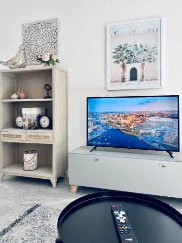 a living room with a flat screen tv on a white cabinet at Stylish Boutique House - Turquoise - Outdoor Yard & Adjoining Cafeteria - Very Central! Near Valletta - Non-Sharing & Quiet in Hamrun