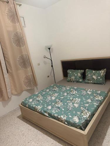ein Schlafzimmer mit einem Bett mit einer grünen Decke und Kissen in der Unterkunft Résidence Zohra in Bin Rhilouf
