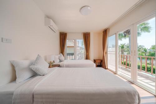 une chambre avec deux lits et une grande fenêtre dans l'établissement บ้านทะเลสำราญ by May, à Cha Am