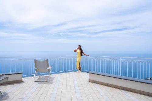 a woman in a yellow dress standing on a balcony at Hotel le Rocce - Agerola, Amalfi Coast in Agerola