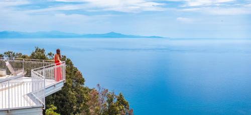 a woman standing on a balcony looking at the water at Hotel le Rocce - Agerola, Amalfi Coast in Agerola