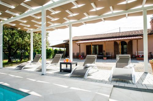 a group of chairs under a pergola next to a pool at Villa Asia, private villa with pool in Panicarola