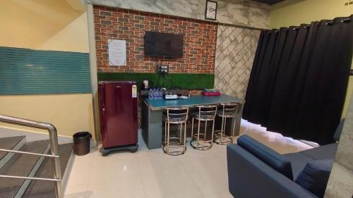 a bar in a room with a refrigerator and stools at The PALM SUITES , Incredible India Tourism in Guwahati
