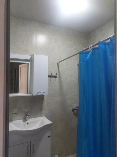 a bathroom with a sink and a blue shower curtain at Batumi in Itʼkhvisi