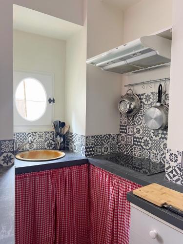 une cuisine avec un évier et un rideau rouge dans l'établissement La Maison d'Alienor Les Beauregards, à Chablis