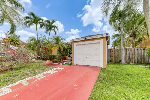 a garage on a red driveway in a yard with palm trees at Golf and Shop Gem with Private Pool in Boca Raton in Boca Raton